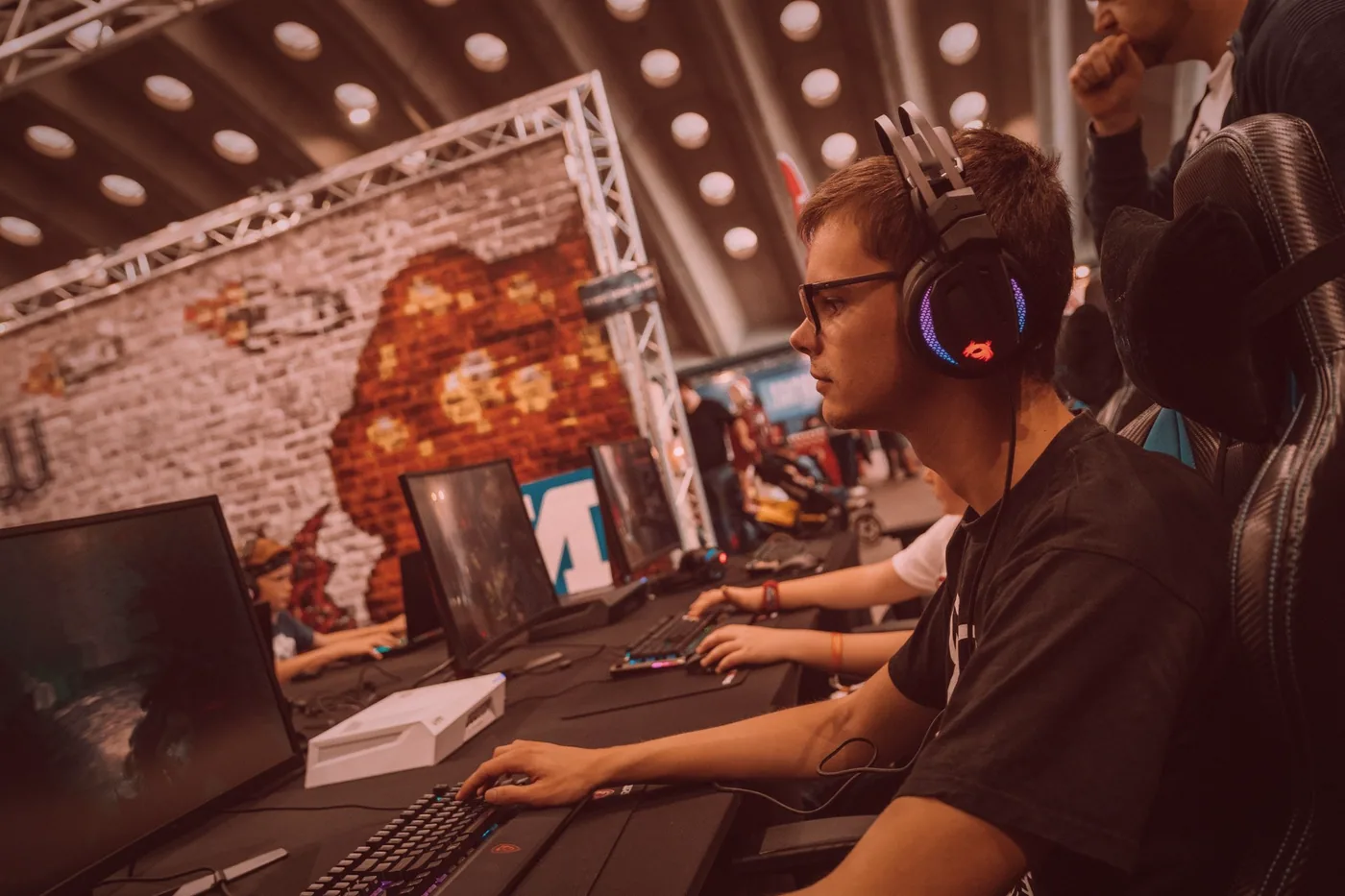 Players and watchers standing around a screen, following a match in progress